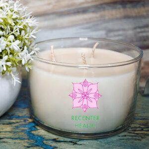 Glass candle with floral decoration and text.