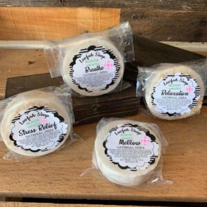 Four packaged handmade soap bars displayed.