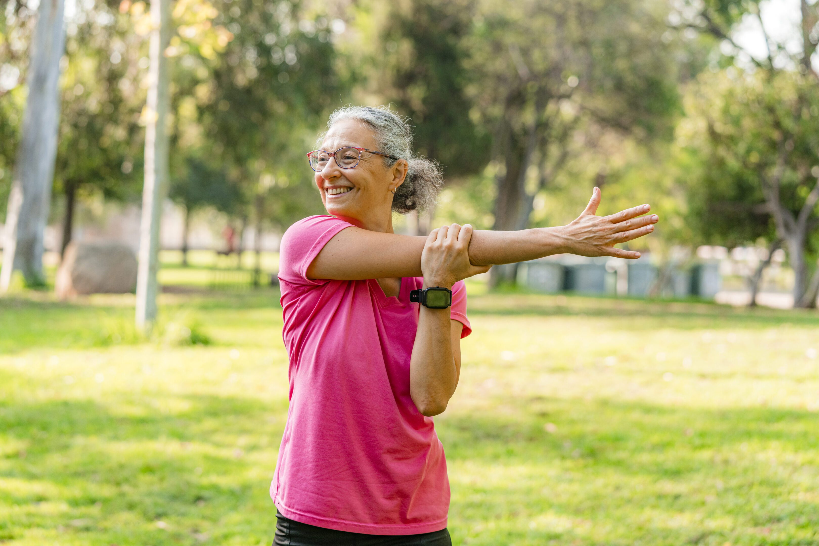 Woman stretching arms in a sunny park.