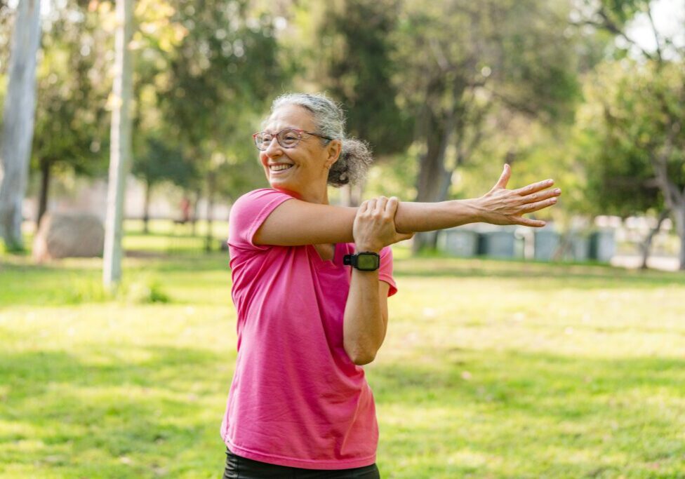 Woman stretching arms in a sunny park.
